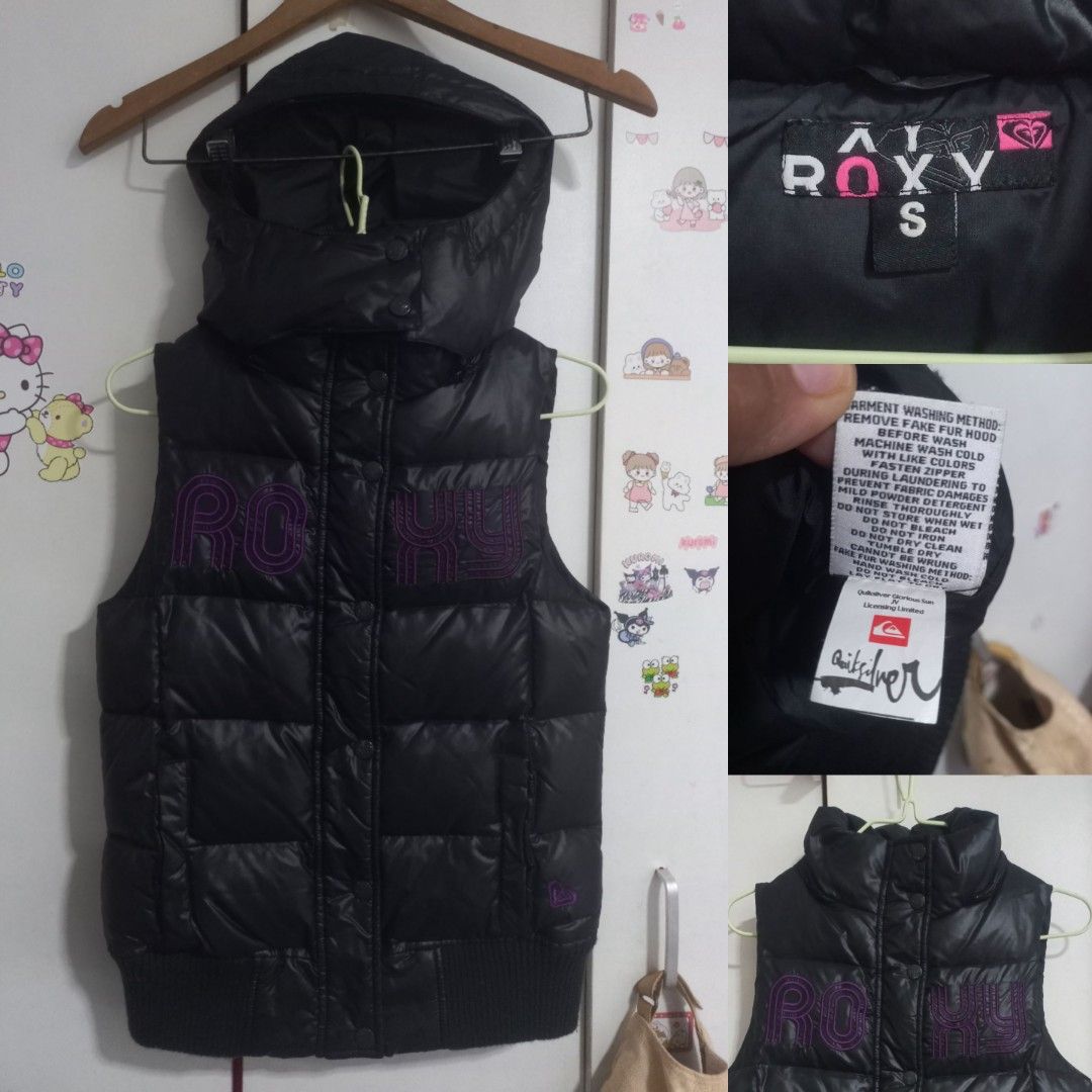 Roxy Black Puffer Vest with Hood Size S (Category: Coats, Jackets and Outerwear) located in Manila. Submitted by maryjoyenc89891 (Listing ID 1464244719, Image 1). Description: - Black Roxy puffer vest - Attached hood for extra warmth - Signature purple Roxy logo on the front - Ribbed cuffs ensure a snug and comfortable fit - Quiksilver branding visible on the inside tag - Ideal for layering over other clothing - Please check photos for detailed c
