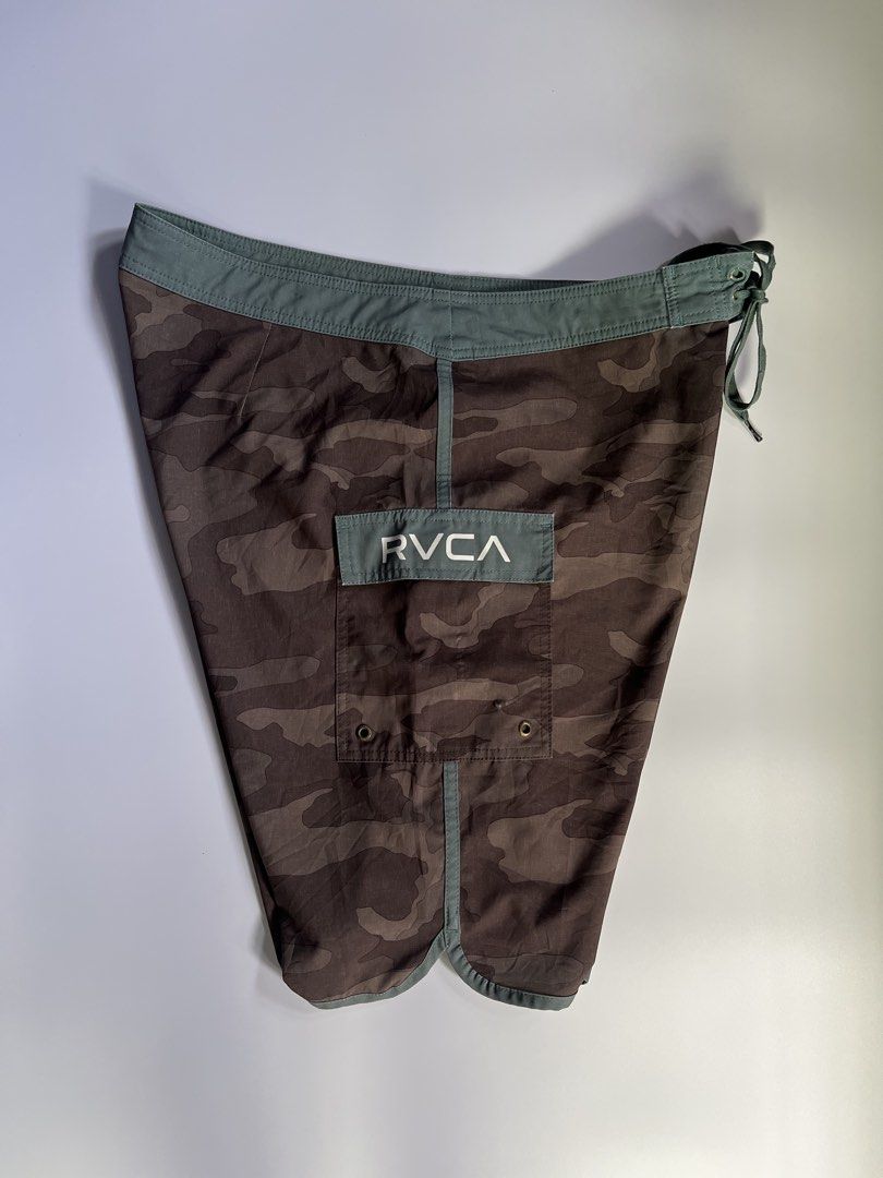 RVCA Camo Board Shorts Size 36 (Category: Swim Trunks & Board Shorts) located in Baler. Submitted by allthrifted31 (Listing ID 1464286770, Image 3). Description: - RVCA Board Shorts - Size: 36 - Stylish camo pattern - Green waistband and trim - Drawstring closure for a secure fit - Back pocket with velcro closure - Side pocket with button closure - Ideal for beach, pool, or any water activity.