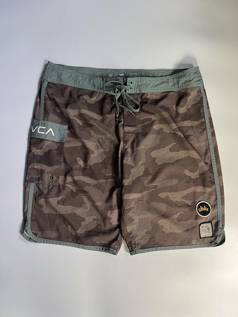 RVCA Camo Board Shorts Size 36 (Category: Swim Trunks & Board Shorts) located in Baler. Submitted by allthrifted31 (Listing ID 1464286770, Image 1). Description: - RVCA Board Shorts - Size: 36 - Stylish camo pattern - Green waistband and trim - Drawstring closure for a secure fit - Back pocket with velcro closure - Side pocket with button closure - Ideal for beach, pool, or any water activity.
