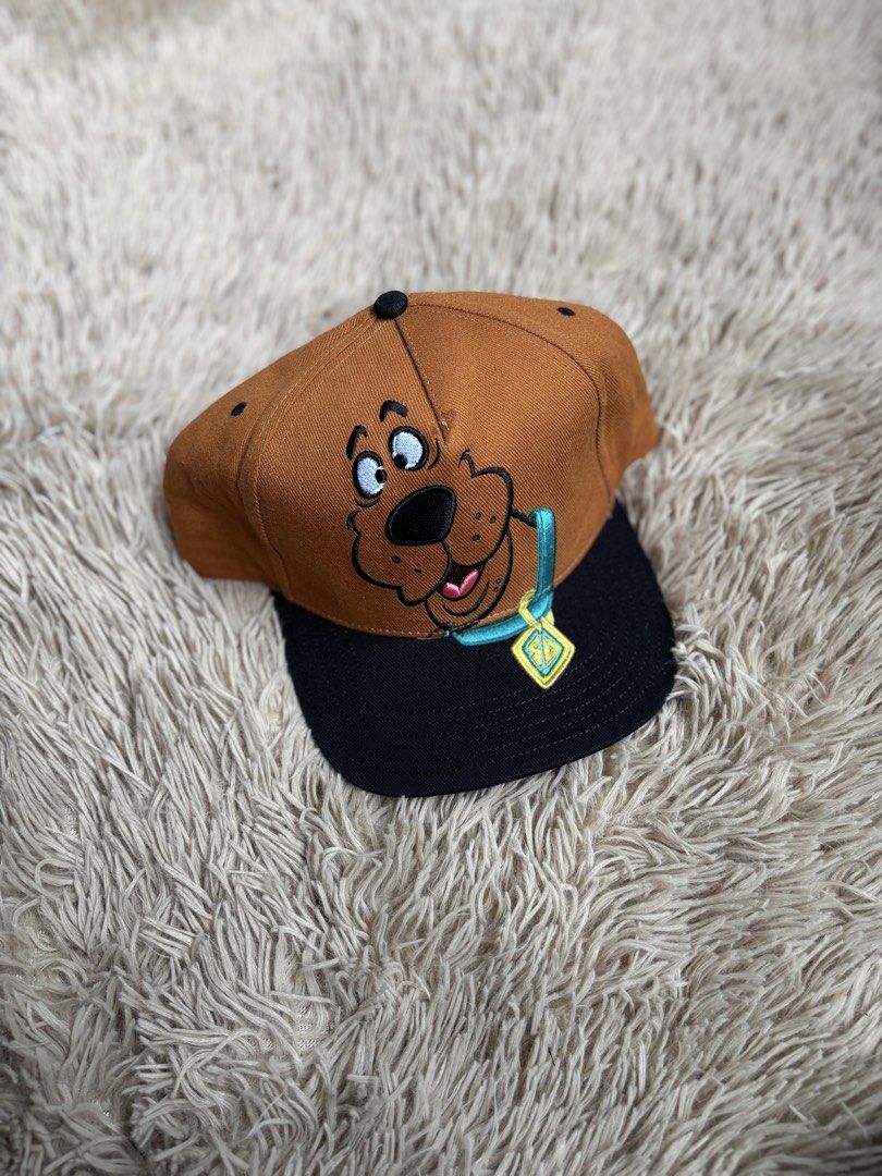 Scooby-Doo Embroidered Snapback Cap (Category: Caps & Hats) located in Quezon City. Submitted by nojthrift (Listing ID 1464251835, Image 1). Description: - Brown and black snapback cap - Features embroidered Scooby-Doo face and iconic tag - Adjustable strap at the back - Ideal for Scooby-Doo fans - Fun accessory for casual outfits.