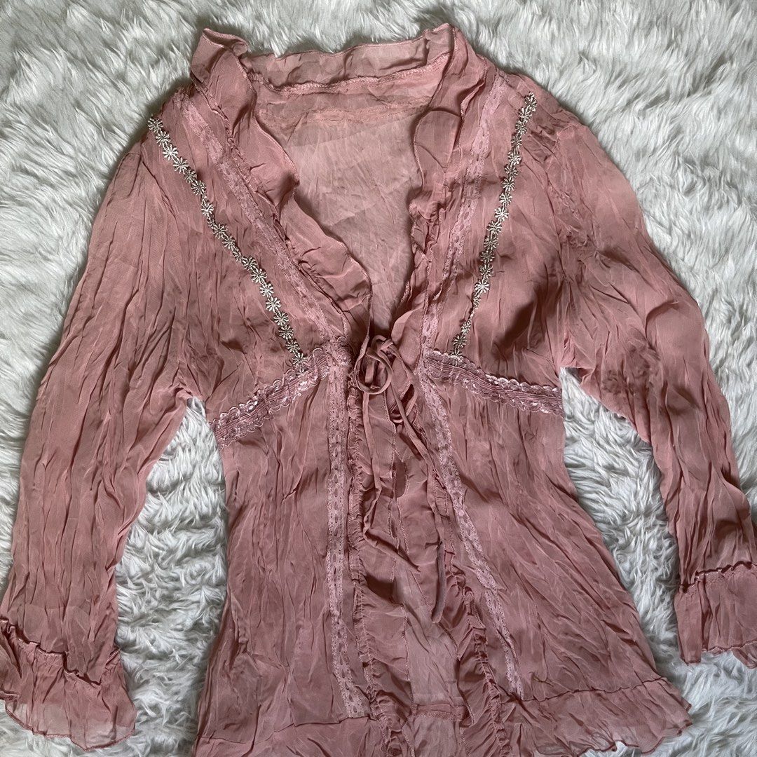 Sheer Pink Blouse with Lace and Tie Front (Category: Blouses) located in Maasin. Submitted by taraa18 (Listing ID 1464297122, Image 2). Description: - Sheer pink long-sleeved blouse - Delicate lace trim along neckline - Floral bead details on neckline - Tie front closure - Crinkled fabric texture - Made in Hong Kong - Ideal for layering or a vintage aesthetic.