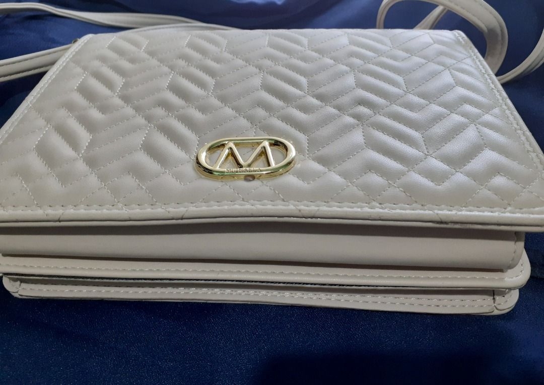 Sling Bag - Michaela (Category: Cross-body Bags) located in Caloocan City. Submitted by noblecat_5a849d (Listing ID 1464230544, Image 1). Description: - Cream colored crossbody bag - Quilted chevron pattern on front flap - Gold-tone metal 'M' logo - Zip closure with a separate compartment - Ideal for everyday wear.