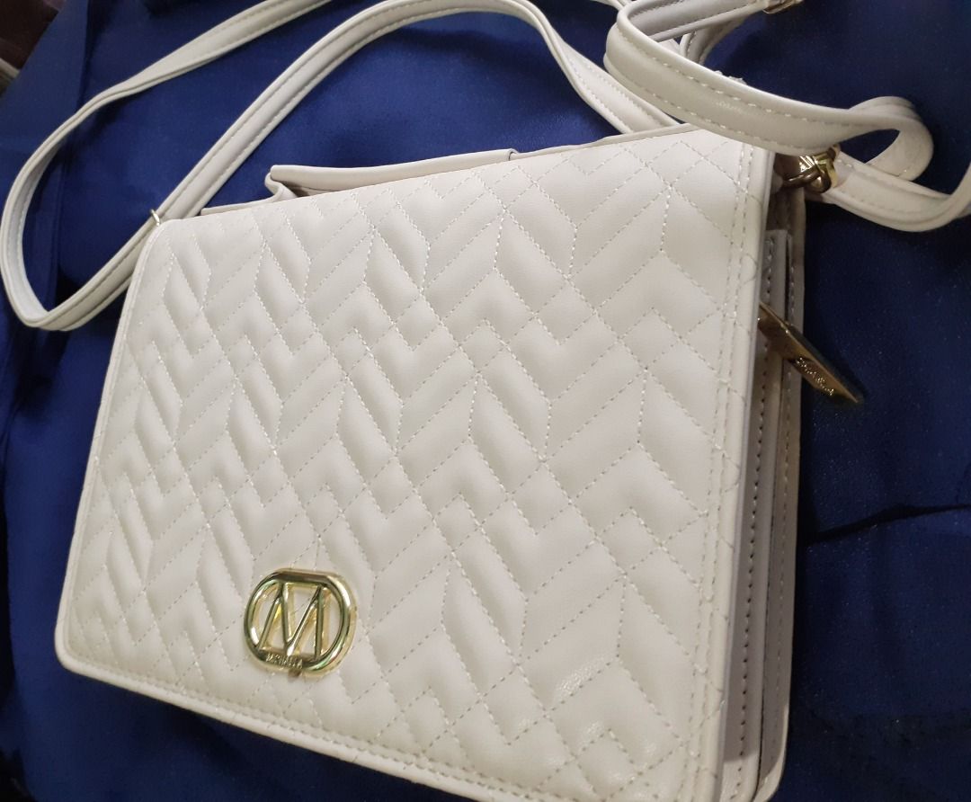 Sling Bag - Michaela (Category: Cross-body Bags) located in Caloocan City. Submitted by noblecat_5a849d (Listing ID 1464230544, Image 2). Description: - Cream colored crossbody bag - Quilted chevron pattern on front flap - Gold-tone metal 'M' logo - Zip closure with a separate compartment - Ideal for everyday wear.