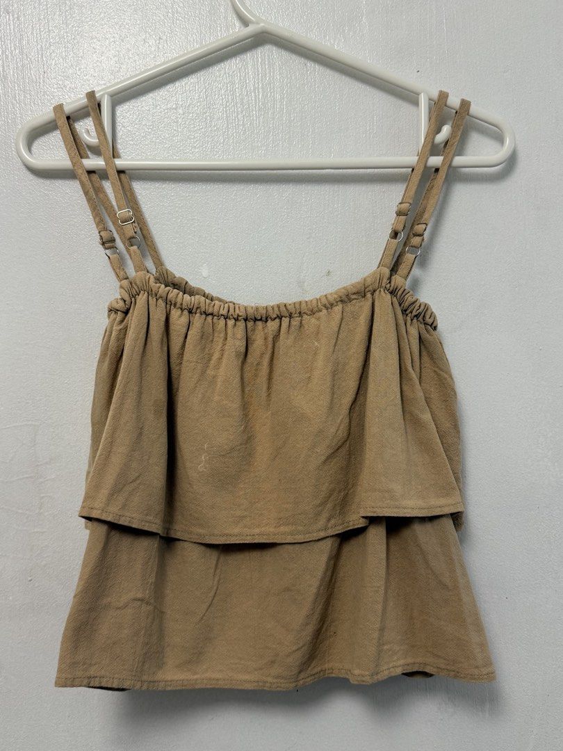 Tan Tiered Ruffle Spaghetti Strap Tank Top (Category: Sleeveless) located in Mandaluyong City. Submitted by nftp24 (Listing ID 1464144741, Image 2). Description: - Cute tan tank top - Tiered ruffle design - Adjustable spaghetti straps with buckle details - Gathered elastic neckline - Versatile: pairs well with shorts or jeans - Ideal for casual outings.