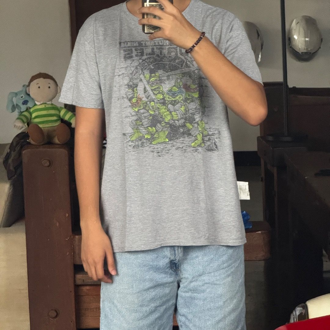 TEENAGE MUTANT NINJA TURTLES (Category: Tshirts & Polo Shirts ) located in Quezon City. Submitted by theq.thriftshop (Listing ID 1464146397, Image 2). Description: PLEASE READ FIRST! MINE ₱349 + sf (FIXED) Size L (L 27”, W 22.5”) Issue: Hole Color may vary due to lighting Model’s height: 5’9 💸 G-Cash payment 📦 J&T Nationwide shipping.