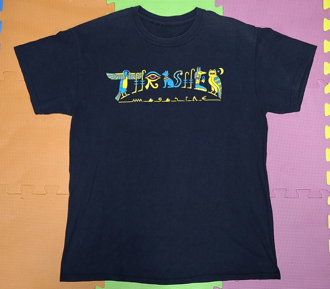 Thrasher Magazine Egyptian Hieroglyphics (Category: Tshirts & Polo Shirts ) located in Manila. Submitted by declutrredgoods (Listing ID 1464283897, Image 1). Description: - Black t-shirt - Features a cool Egyptian-inspired graphic on the front - Graphic includes birds, an eye, a cat, and other symbols - Colors: Blue and Yellow - Ideal for casual wear.