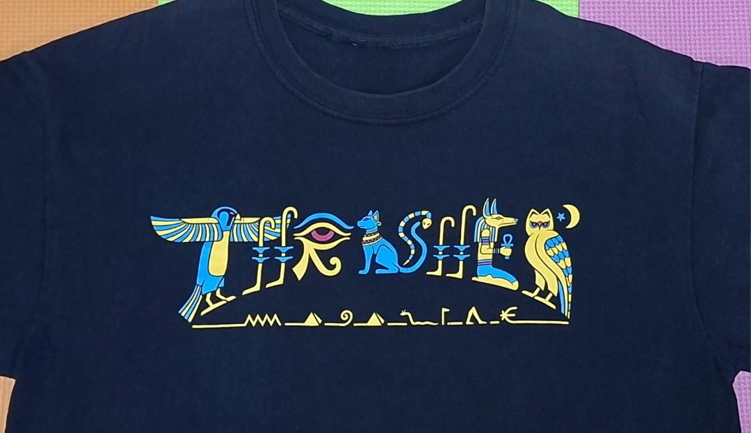 Thrasher Magazine Egyptian Hieroglyphics (Category: Tshirts & Polo Shirts ) located in Manila. Submitted by declutrredgoods (Listing ID 1464283897, Image 2). Description: - Black t-shirt - Features a cool Egyptian-inspired graphic on the front - Graphic includes birds, an eye, a cat, and other symbols - Colors: Blue and Yellow - Ideal for casual wear.
