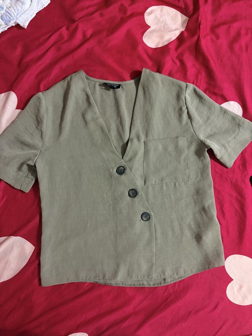 TOPSHOP Olive Green Cropped Button Front Shirt Top (Category: Shirts) located in Munoz. Submitted by Liiz27 (Listing ID 1464260163, Image 3). Description: - Olive green cropped shirt - Brand: Topshop - V-neckline - Button-front closure - Single chest pocket (left side) - Short sleeves with cuffed hem - Versatile: pairs well with high-waisted bottoms.