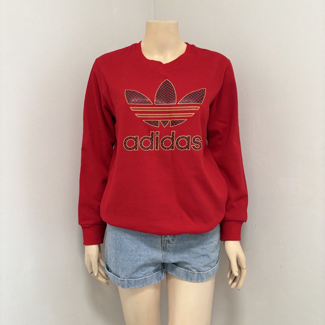 Unisex Adidas Red Sweater (Category: Coats, Jackets and Outerwear) located in Imus. Submitted by reloved.nd (Listing ID 1464244441, Image 1). Description: - Classic red Adidas sweatshirt - Features iconic trefoil logo with a unique patterned fill - Long sleeves and crew neck design - Ideal for casual wear - Pairs well with jeans or shorts.