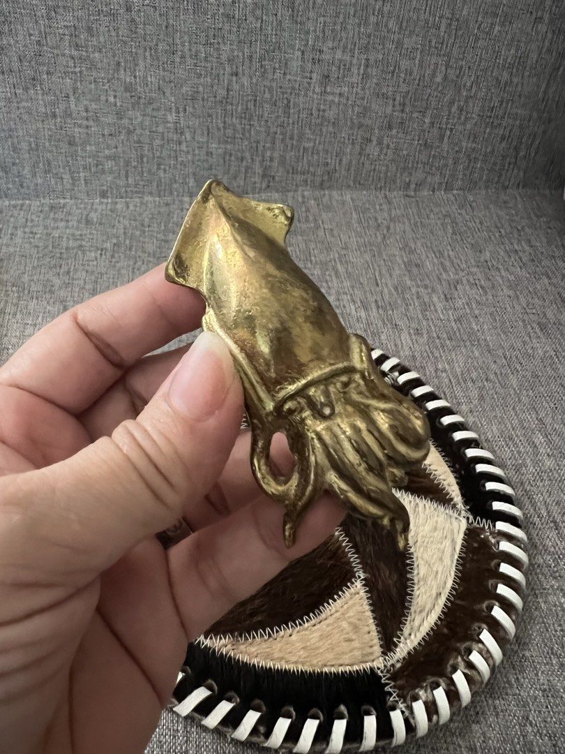 Vintage Brass Squid Figurine on Patchwork Coaster (Category: Vintage Collectibles) located in Las Pinas. Submitted by maple0305 (Listing ID 1464180056, Image 3). Description: - Unique brass squid figurine - Attached to a round coaster made of stitched animal hide patches - Coaster features a black and white striped edge - Great conversation piece for desk or shelf - Measures approximately 6 inches in diameter - Brass has a nice, aged patina - Qui
