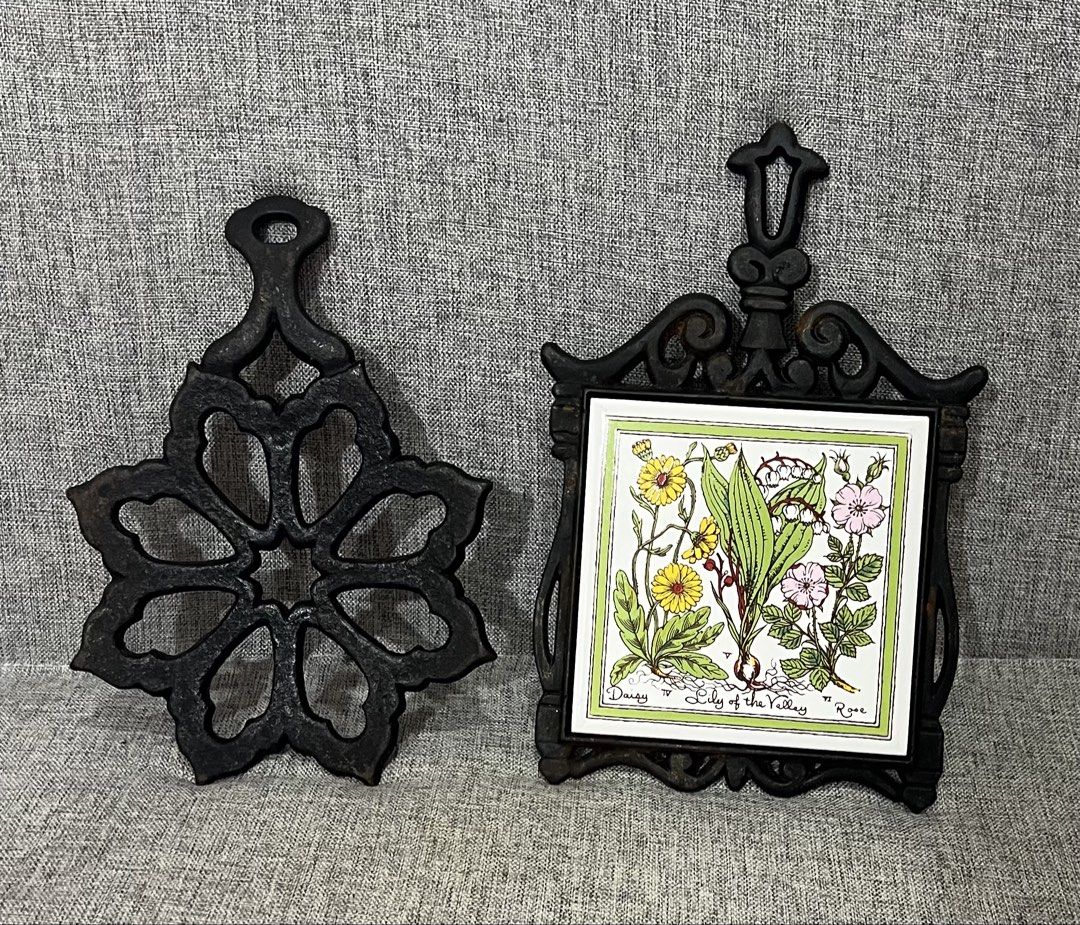 Vintage Cast Iron Trivets with Ceramic Tile Insert (Category: Cookware & Accessories) located in Las Pinas. Submitted by maple0305 (Listing ID 1464192600, Image 3). Description: - Set of 2 vintage cast iron trivets - One features a decorative floral cut-out design - Second trivet has a ceramic tile with botanical illustration (daisies, lily of the valley, roses) - Both have a rustic, antique charm - Ideal for protecting countertops and tables fro