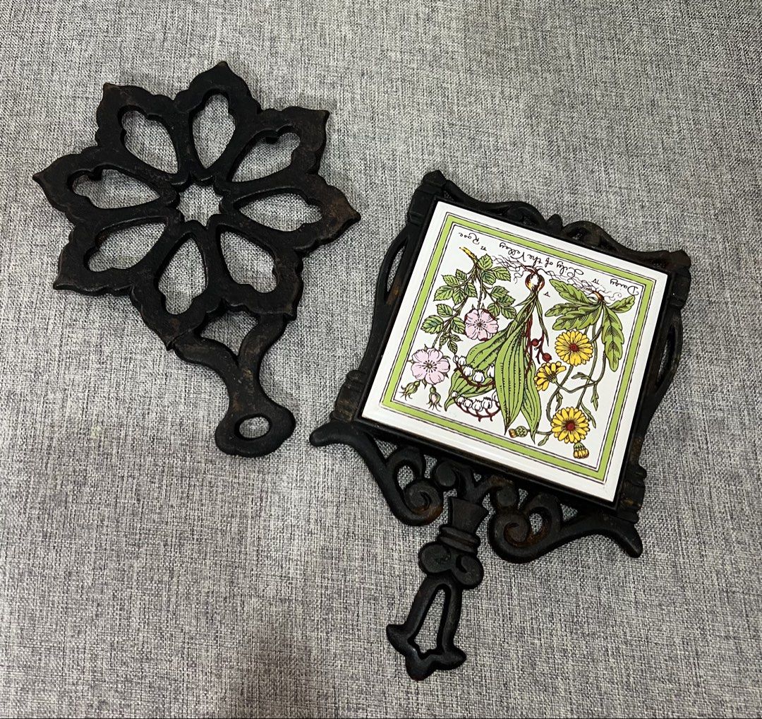 Vintage Cast Iron Trivets with Ceramic Tile Insert (Category: Cookware & Accessories) located in Las Pinas. Submitted by maple0305 (Listing ID 1464192600, Image 1). Description: - Set of 2 vintage cast iron trivets - One features a decorative floral cut-out design - Second trivet has a ceramic tile with botanical illustration (daisies, lily of the valley, roses) - Both have a rustic, antique charm - Ideal for protecting countertops and tables fro
