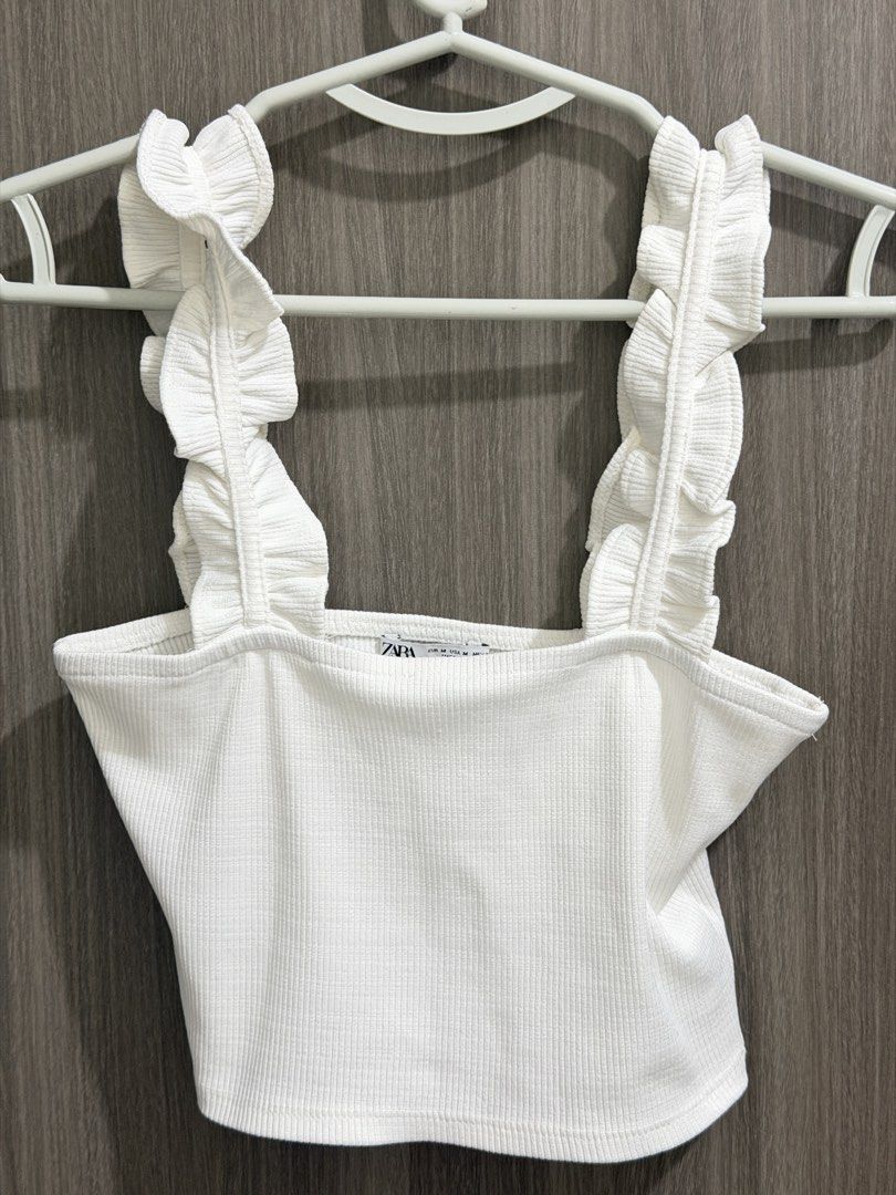 Zara White Ribbed Ruffle Strap Crop Top Size M (Category: Sleeveless) located in Manila. Submitted by ktyyycloset (Listing ID 1464248348, Image 3). Description: - White ribbed crop top from Zara - Features cute ruffle straps - Square neckline - Versatile: pairs well with jeans or skirts - Ideal for casual outings or nights with friends - Size: Medium.