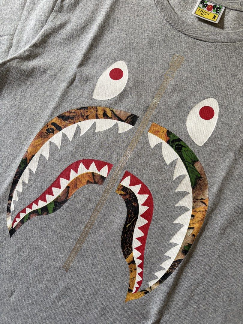 A Bathing Ape BAPE Shark Tee Grey Size M (Category: Tshirts & Polo Shirts ) located in Midsayap. Submitted by monesreenc98619 (Listing ID 1464405041, Image 2). Description: - Grey BAPE T-Shirt - Iconic Shark Graphic (mouth design) - Camouflage & Tiger Print Details - Comfortable Cotton Material - Size: Medium (M) - Ideal for Streetwear Enthusiasts.