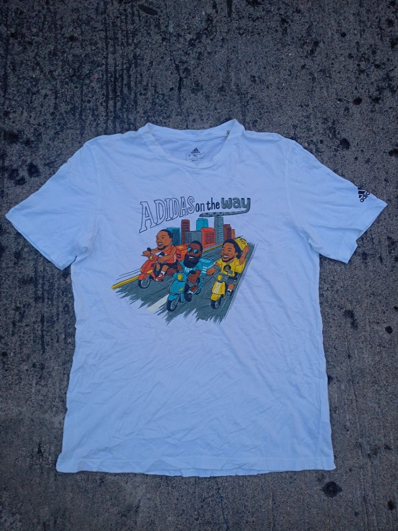 Adidas "On The Way" Graphic Tee White (Category: Tshirts & Polo Shirts ) located in Caloocan City. Submitted by eragamisch70090 (Listing ID 1464522484, Image 1). Description: - White Adidas T-shirt - Fun graphic print on front: cartoon characters riding scooters in a city - Adidas logo detail on sleeve - Ideal for casual and everyday wear.