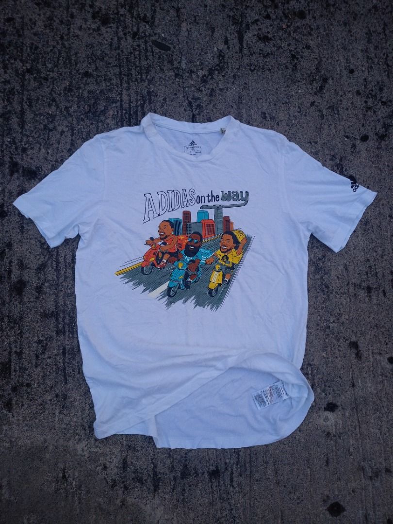 Adidas "On The Way" Graphic Tee White (Category: Tshirts & Polo Shirts ) located in Caloocan City. Submitted by eragamisch70090 (Listing ID 1464522484, Image 2). Description: - White Adidas T-shirt - Fun graphic print on front: cartoon characters riding scooters in a city - Adidas logo detail on sleeve - Ideal for casual and everyday wear.
