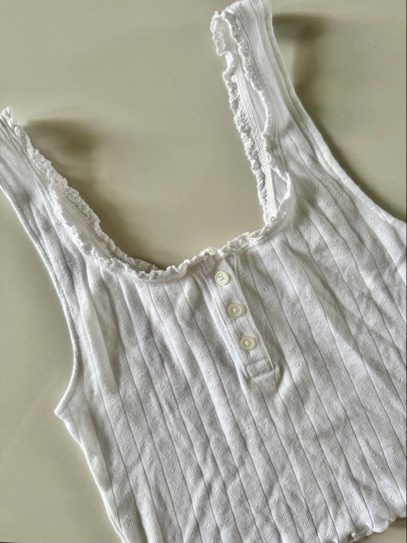 American Eagle White Ribbed Lettuce Hem Tank Top (Category: Sleeveless) located in Bulacan. Submitted by _arislmt (Listing ID 1464418084, Image 1). Description: - White ribbed tank top from American Eagle - Features a lettuce hem - Button-up front - Cropped fit - Comfortable and breathable fabric - Great for casual wear or layering - Fits XS.