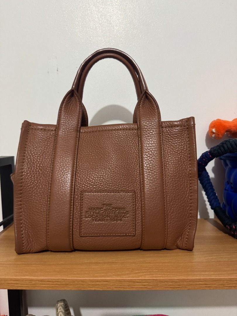 AUTHENTIC Marc Jacobs The Tote Bag Mini / Small - Argan Oil (Category: Tote Bags) located in Quezon City. Submitted by afpar (Listing ID 1464495010, Image 3). Description: - Purchased from Farfetch - Some signs of usage on the corners, but not too obvious - Comes with a free guitar strap in Argan Oil too.
