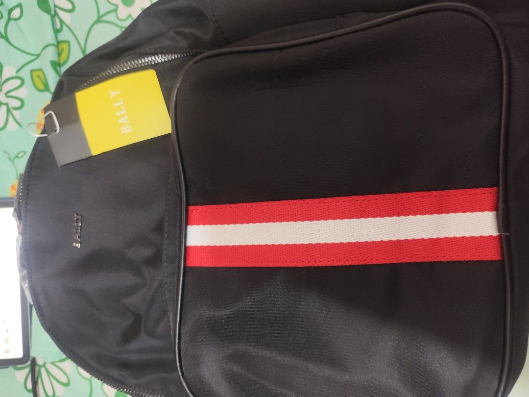 Bally Black Nylon Backpack with Red and White Stripe (Category: Backpacks) located in Manila. Submitted by marriage031073advocate (Listing ID 1464436321, Image 1). Description: - UNISEX - BRAND NEW - Bally backpack in black nylon - Signature red and white stripe detail on front pocket - Main zippered compartment - Additional front zippered pocket - Adjustable shoulder straps - Comes with tags attached.