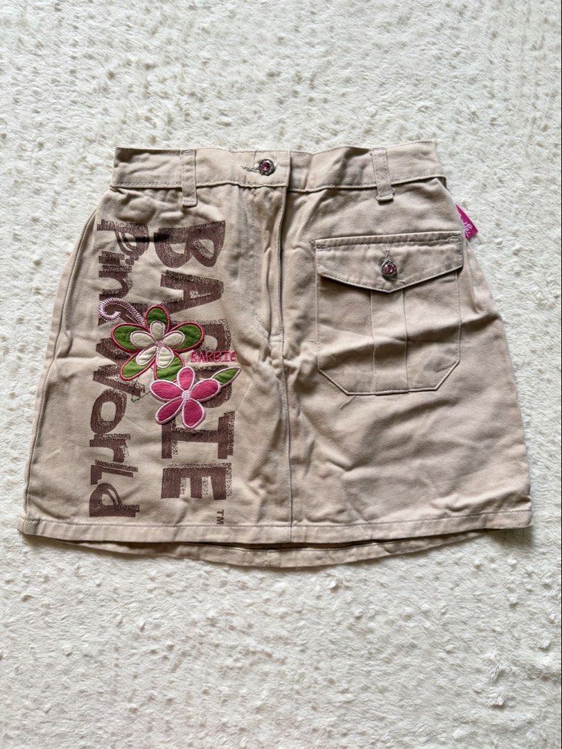 Barbie Cargo Skirt kids (Category: Skirts) located in Tagaytay City. Submitted by melissamm0237 (Listing ID 1464400638, Image 1). Description: - Cute tan cargo skirt from Barbie World. - Features embroidered flowers and 'Barbie World' text. - Convenient pocket on the right side. - Comfortable elastic waistband at the back. - Ideal for casual wear. - Tag size: 10 years..
