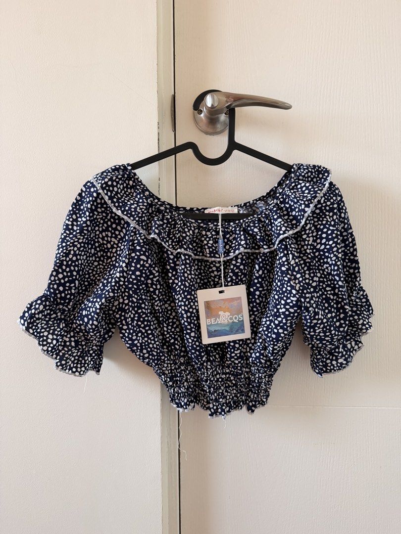 BEA&CQS Navy and White Off Shoulder Crop Top (Category: Blouses) located in Manila. Submitted by pvreal (Listing ID 1464443096, Image 1). Description: - Brand: BEACO&COS - Style: Off-shoulder crop top - Color: Navy blue with white spots print - Features: Ruffled neckline, elasticated hem, short puff sleeves with ruffled cuffs - Occasion: Casual day out, beach trip - Styling: Easy to pair with shorts or jeans.