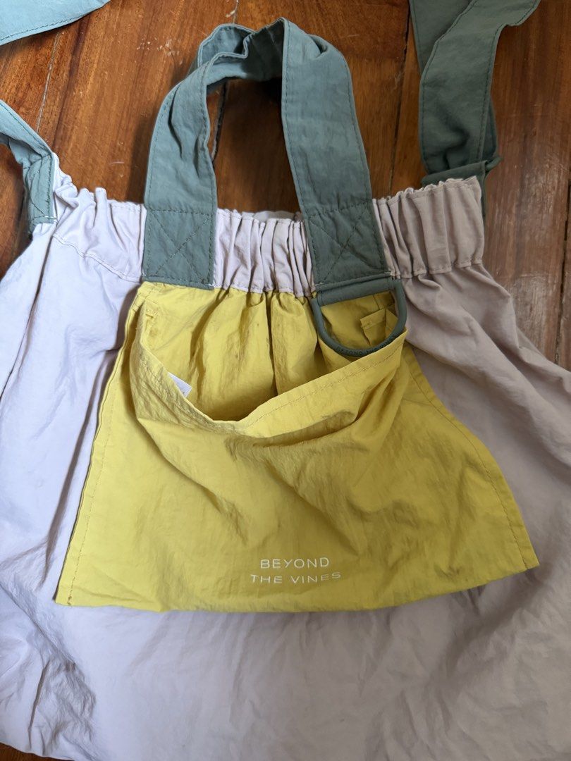 Beyond The Vines DUMPLING Tri color XL (Category: Tote Bags) located in Manila. Submitted by sgdk0115 (Listing ID 1464565114, Image 2). Description: - Brand: Beyond The Vines - Color: Light purple main bag, bright yellow front pocket - Features: Gathered top, green straps, front pocket with brand name - Material: Lightweight - Versatile: Can be worn as a shoulder bag or tote - Ideal for: Everyday use RFS: decluttering Flaws: little dirt in the po