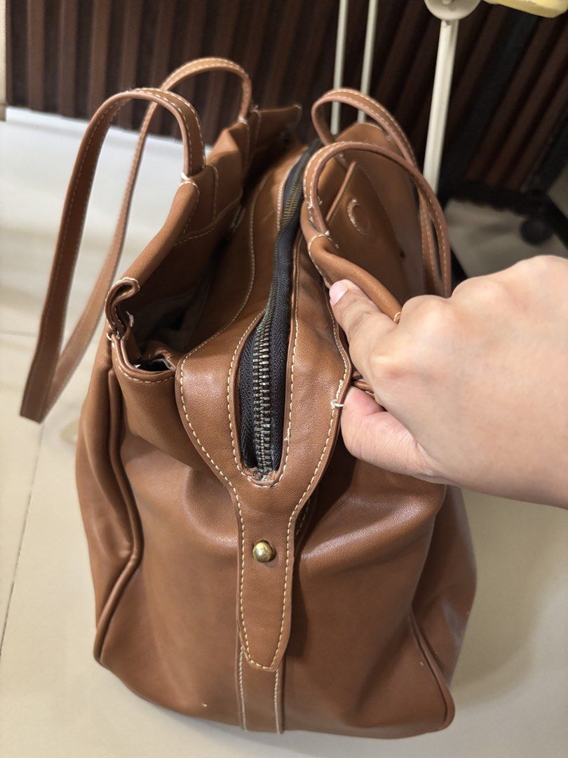 Brown Leather Tote Bag (Category: Tote Bags) located in Manila. Submitted by guivslove04106 (Listing ID 1464392560, Image 2). Description: - Spacious brown tote bag - Made of durable faux leather - Zippered main compartment for security - Internal pockets for easy organization - Comfortable shoulder straps - Ideal for everyday use or travel - Minor marks on leather, as shown in the last photo Location las pinas.