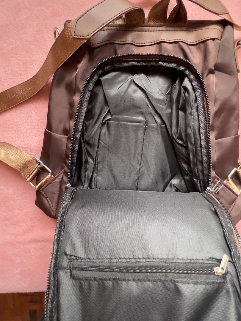 Brown Nylon Backpack with Gold Accents (Category: Backpacks) located in Batangas. Submitted by alaisaampa7513 (Listing ID 1464569885, Image 3). Description: - Durable brown nylon backpack - Convenient front zip pocket - Handy side pockets for easy access - Spacious main compartment with internal organization pockets - Adjustable straps for a comfortable fit - Stylish gold logo accent on the front - Ideal for everyday adventures and errands.