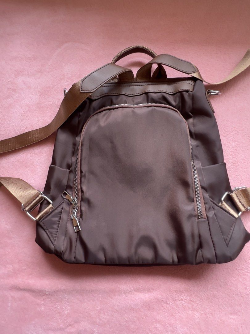 Brown Nylon Backpack with Gold Accents (Category: Backpacks) located in Batangas. Submitted by alaisaampa7513 (Listing ID 1464569885, Image 2). Description: - Durable brown nylon backpack - Convenient front zip pocket - Handy side pockets for easy access - Spacious main compartment with internal organization pockets - Adjustable straps for a comfortable fit - Stylish gold logo accent on the front - Ideal for everyday adventures and errands.