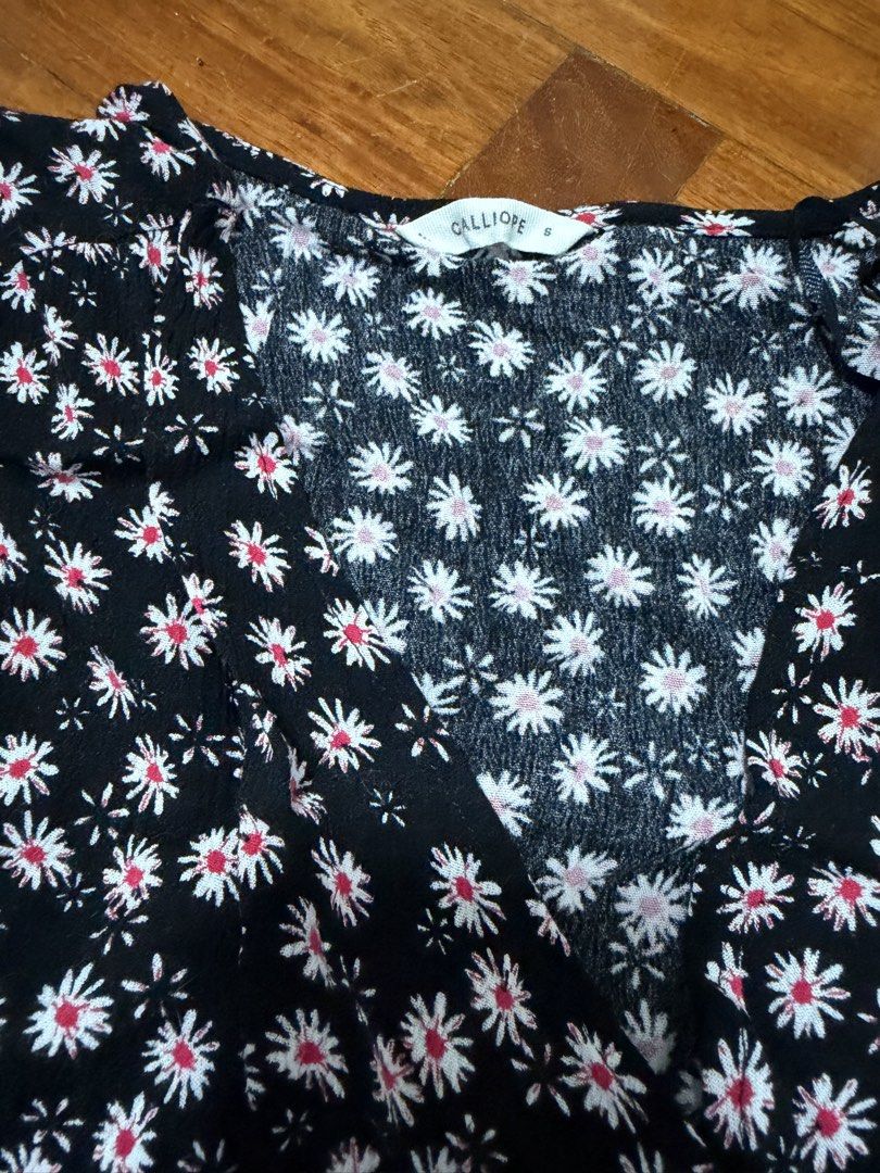 Calliope Black Daisy Print Wrap Top Size S (Category: Blouses) located in Paranaque City. Submitted by ferrewr (Listing ID 1464460510, Image 2). Description: - Cute black top with white and red daisy print - Wrap style with side tie details - Short sleeves - V-neckline - Versatile for casual outings or dressing up.