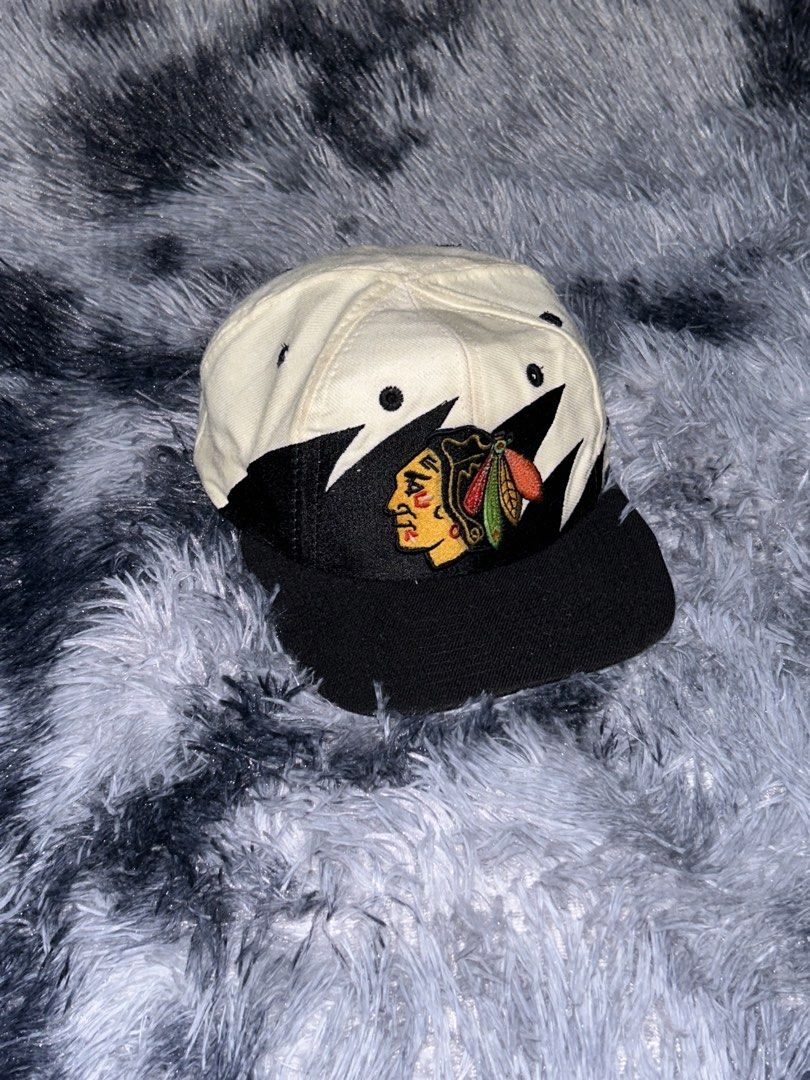 Chicago 90s Blackhawks Sharktooth Logo Athletic Cap (Category: Caps & Hats) located in Cadiz. Submitted by jaybatiller (Listing ID 1464384808, Image 3). Description: - Vintage Chicago Blackhawks cap - Classic Blackhawks logo on front - Black brim and white crown - Logo Athletic branding on side - Adjustable strap for a custom fit - Shows some signs of wear, adding to its vintage charm - Perfect for any Blackhawks fan!.