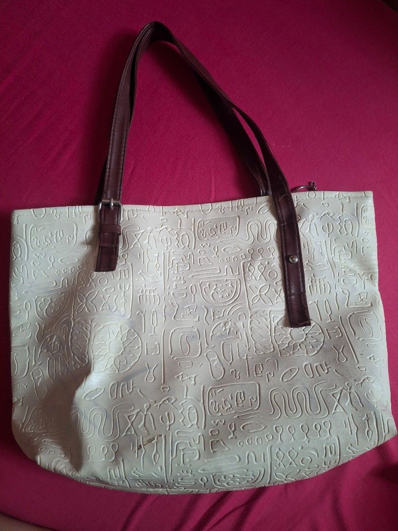 Cream Embossed Tote Bag with Brown Straps (Category: Tote Bags) located in Plaridel. Submitted by niannyyy (Listing ID 1464396097, Image 3). Description: - Chic cream-colored tote bag - Slight flaws and marks - Features an all-over embossed pattern resembling hieroglyphics or ancient symbols - Durable brown faux leather straps - Interior includes a zippered pocket and a slip pocket for organization - Secure zipper closure on top - Ideal size for 