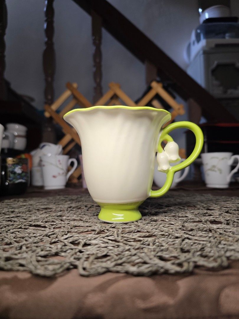 Lily of the Valley Mug (Category: Coffee & Tea Tableware) located in Zamboanga. Submitted by lunavinum (Listing ID 1464443733, Image 1). Description: - peronal fave - Features delicate sculpted lily of the valley flowers on the handle. - Cream white with a fluted design. - Vibrant green rim and base. - Adds a charming touch to any table setting. - approx meas 3.3x4.1.