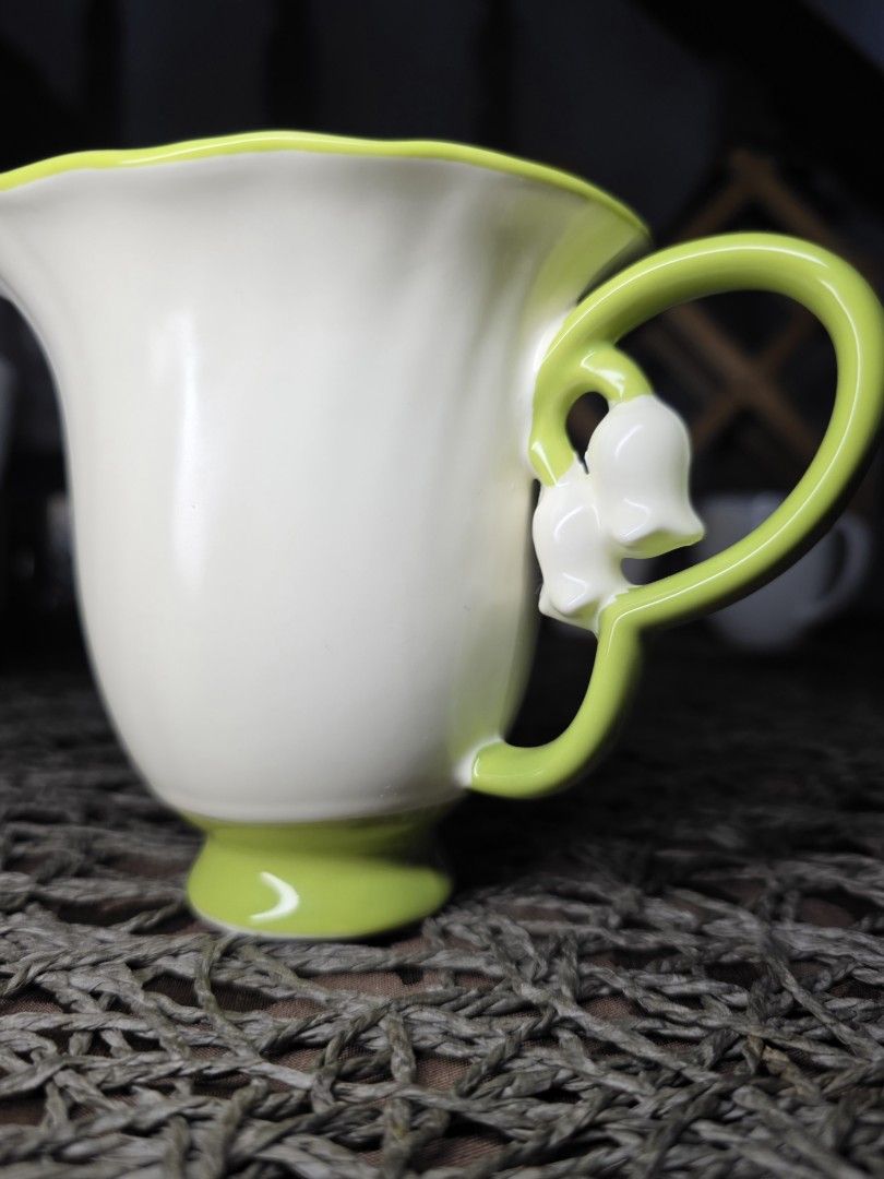 Lily of the Valley Mug (Category: Coffee & Tea Tableware) located in Zamboanga. Submitted by lunavinum (Listing ID 1464443733, Image 3). Description: - peronal fave - Features delicate sculpted lily of the valley flowers on the handle. - Cream white with a fluted design. - Vibrant green rim and base. - Adds a charming touch to any table setting. - approx meas 3.3x4.1.
