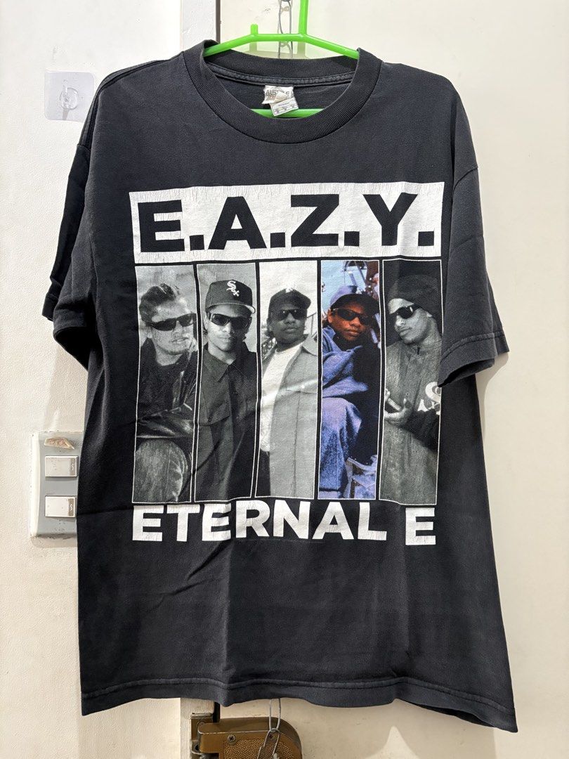 Eazy-E Eternal E T-Shirt (Category: Tshirts & Polo Shirts ) located in Manila. Submitted by dominicoab75406 (Listing ID 1464373366, Image 1). Description: - Classic black t-shirt - Features Eazy-E graphic print - Includes 'E.A.Z.Y.' and 'ETERNAL E' text - Depicts iconic Eazy-E and N.W.A. members - Ideal for hip-hop enthusiasts - A must-have addition to your collection.
