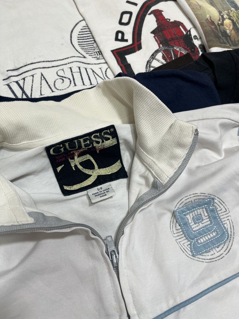 Guess White Track Jacket S/P (Category: Coats, Jackets and Outerwear) located in Baao. Submitted by plainclothesdept (Listing ID 1464534232, Image 2). Description: Guèss Full Zip Tracker Jacket width - 22 in. length - 24 in. discoloration, stains - White Guess track jacket - Blue and tan stripes on sleeves - Zip-up front with pockets - Size: S/P - Made in China - Perfect for casual wear.