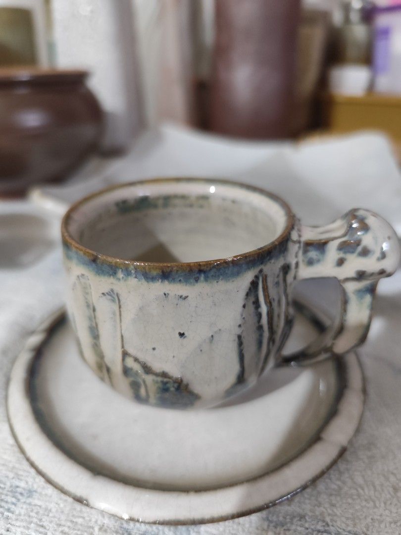 Handmade Ceramic Mug and Saucer Set (Category: Coffee & Tea Tableware) located in Manila. Submitted by marriage031073advocate (Listing ID 1464421756, Image 1). Description: - Unique handmade ceramic mug and saucer set. - Beautiful off-white glaze with charming blue and brown accents. - Features a textured exterior for a unique feel. - Designed with a comfortable handle for easy grip. - Ideal for your daily coffee or tea rituals. - Conveniently di