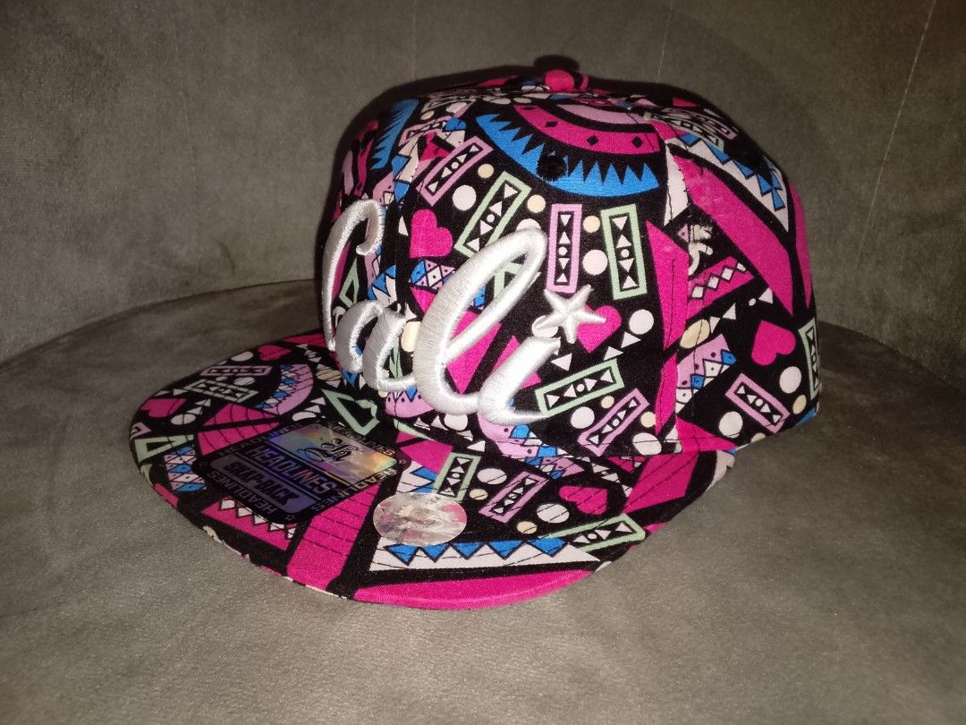 Headlines Cali 90s Aztec Geometric Print Pink Black Snapback Hat (Category: Caps & Hats) located in Binangonan. Submitted by yuristalin888 (Listing ID 1464397589, Image 2). Description: Vibrant 90s-style Aztec geometric and abstract pattern featuring bright pink, black, blue, and green tones, highlighted by a large embroidered white "Cali" script logo on the front crown. * **Style:** Structured flat-brim snapback cap complete with the original "H
