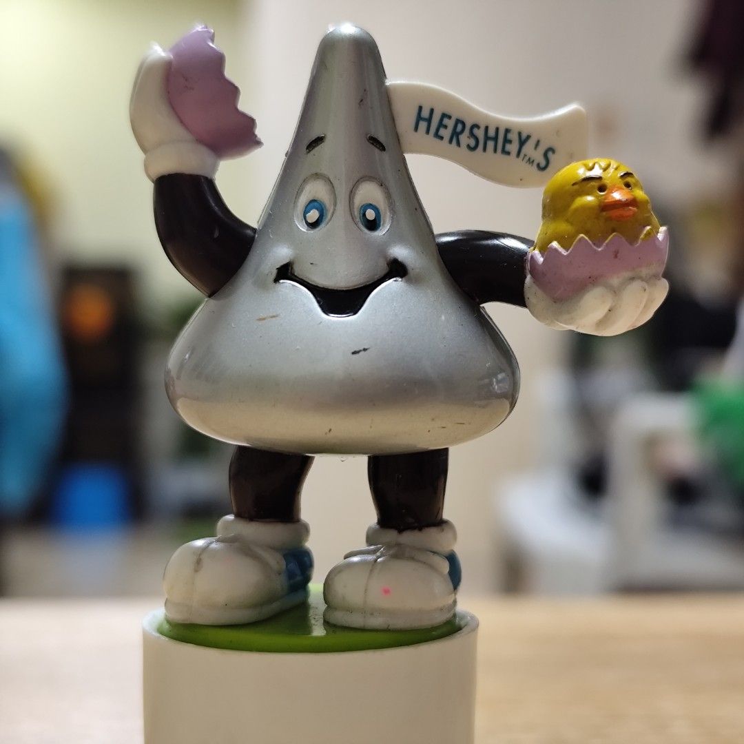 Hershey's Kiss Easter Chick & Egg Figurine (Category: Figurines & Statues) located in Rizal. Submitted by mamamamawskey_031284 (Listing ID 1464535075, Image 2). Description: - Adorable Hershey's Kiss character dressed for Easter. - Holding a chick hatching from an egg and a broken Easter egg. - Features a "HERSHEY'S" banner. - Stands on a white base. - Ideal for Easter decorations. - A must-have for Hershey's collectors. - Fun and collectible pie