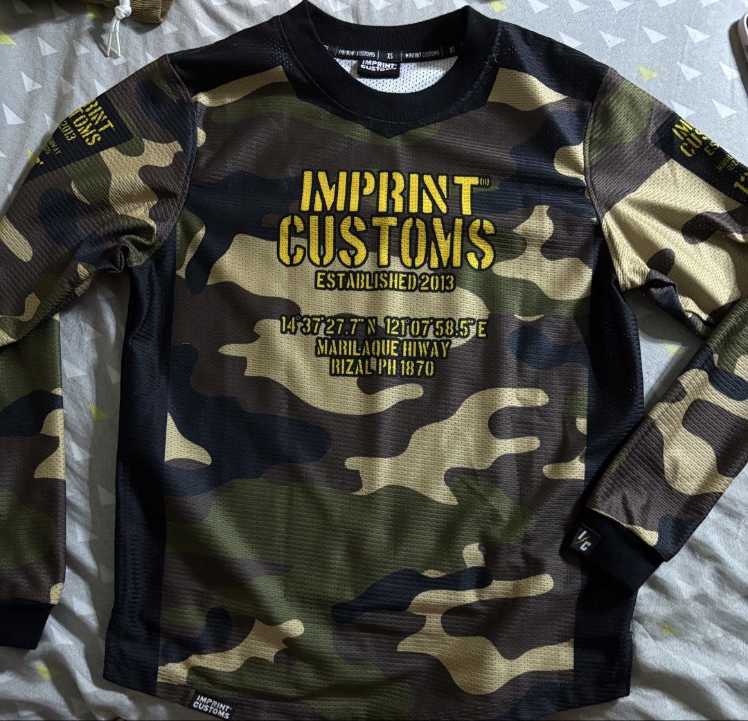Imprint Customs Camo Long Sleeve Shirt (Category: Tshirts & Polo Shirts ) located in Caloocan City. Submitted by clang17. (Listing ID 1464385592, Image 2). Description: - Long sleeve shirt from Imprint Customs - Features a camouflage pattern with yellow text - Established in 2013 - Located in Marilao -way, Rizal - Visit imprintcustomsph.com for more info - Ideal for casual wear or outdoor activities.
