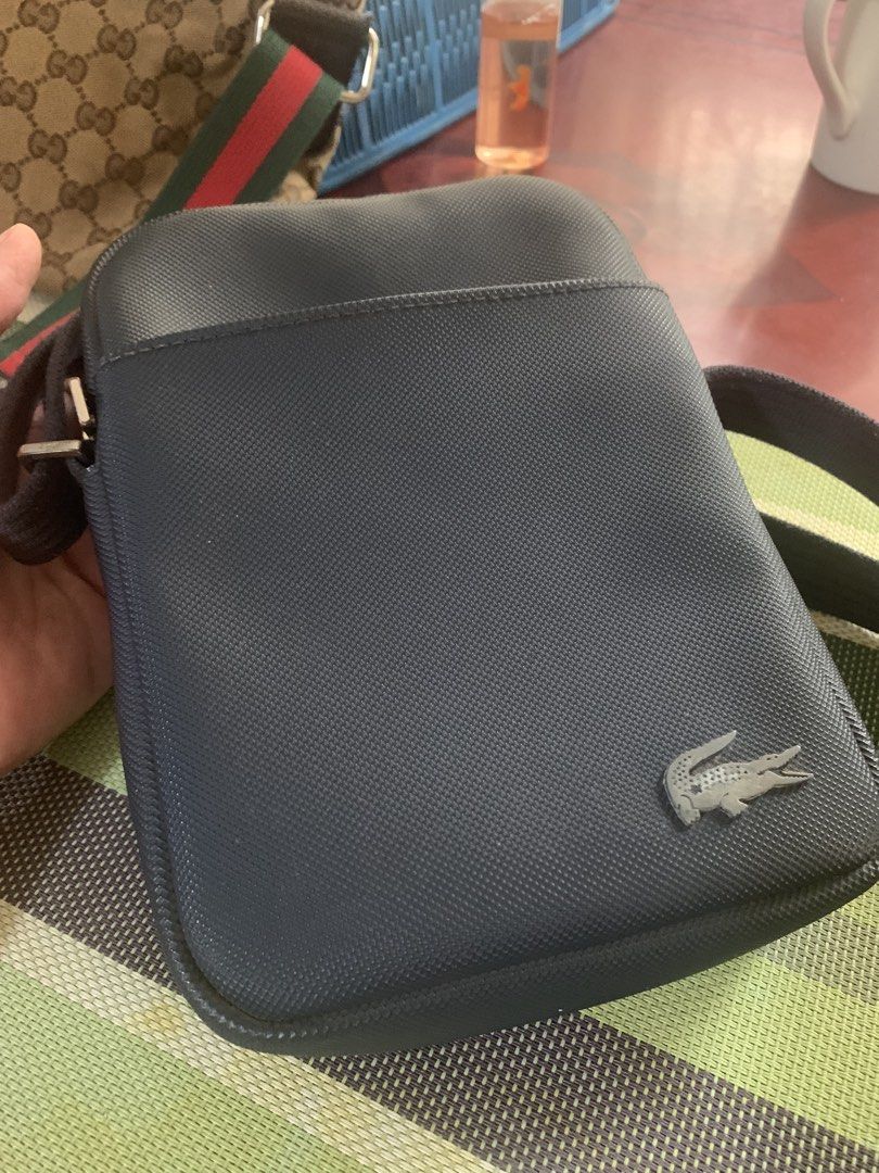 Lacoste Crossbody Bag Original (Category: Cross-body Bags) located in Paranaque City. Submitted by declutterby4angels (Listing ID 1464386916, Image 2). Description: - Dark blue Lacoste crossbody bag - Textured material with iconic crocodile logo - Adjustable strap for comfortable wear - Ideal for everyday use, keeping essentials handy - Clean and simple design.