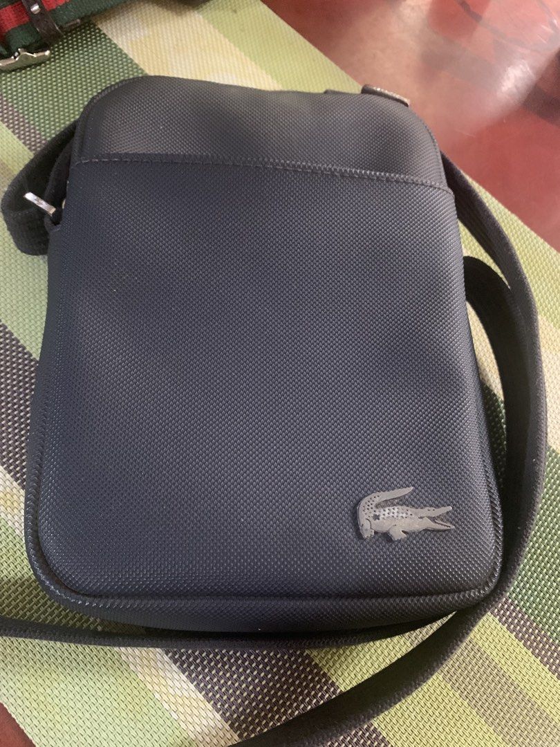 Lacoste Crossbody Bag Original (Category: Cross-body Bags) located in Paranaque City. Submitted by declutterby4angels (Listing ID 1464386916, Image 1). Description: - Dark blue Lacoste crossbody bag - Textured material with iconic crocodile logo - Adjustable strap for comfortable wear - Ideal for everyday use, keeping essentials handy - Clean and simple design.