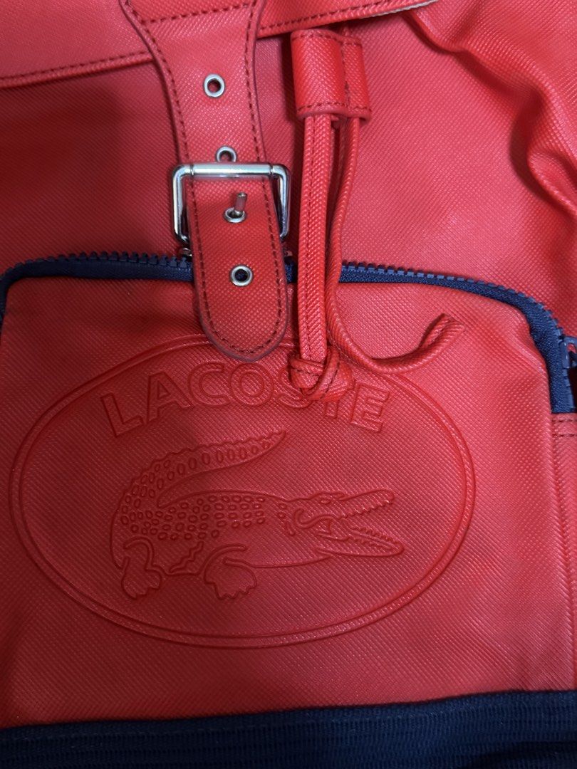 Lacoste Red Backpack with Navy Trim (Category: Backpacks) located in Paranaque City. Submitted by nynrecto (Listing ID 1464466881, Image 2). Description: - Classic red Lacoste backpack - Iconic embossed crocodile logo on front pocket - Stylish navy blue trim and straps - Secure buckle closure on the flap - Convenient zipped front pocket - Ideal for everyday use and errands.