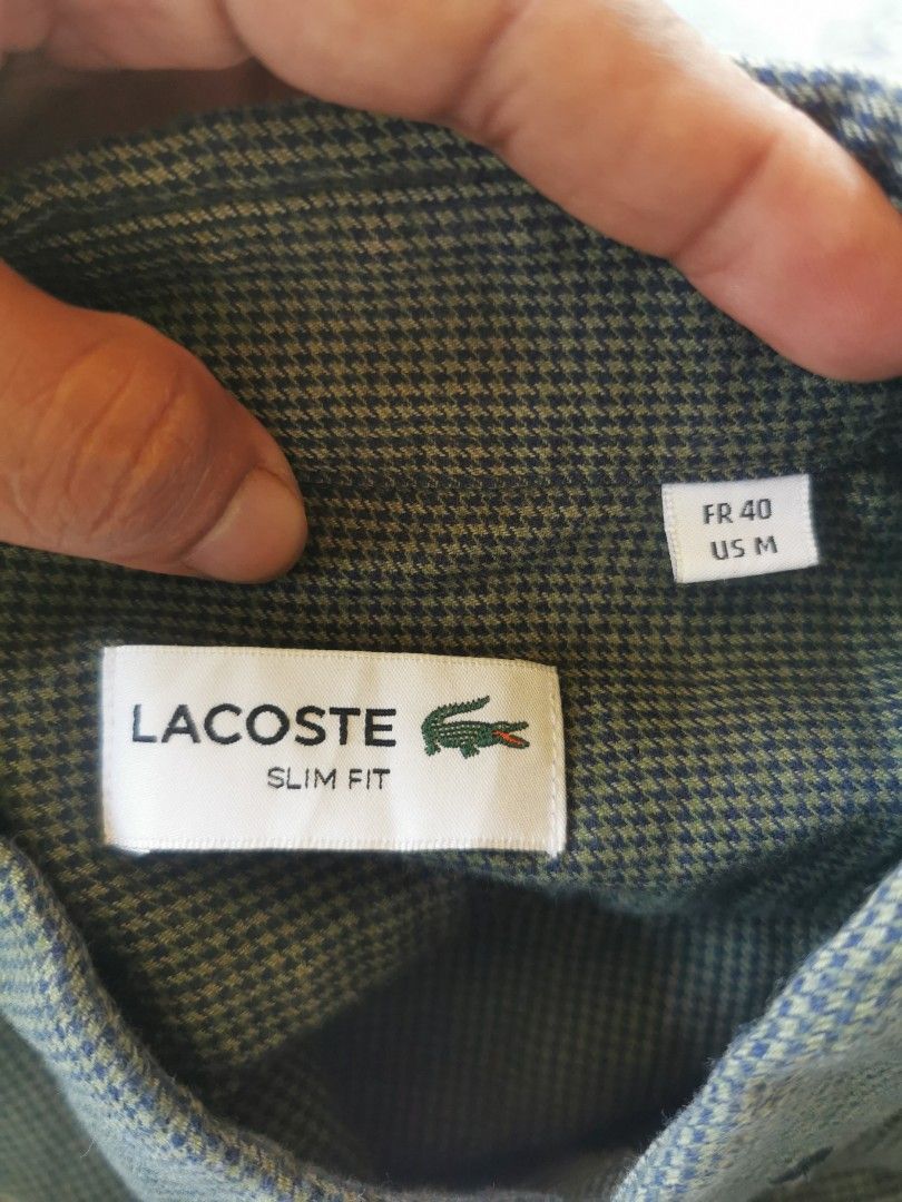 Lacoste Slim Fit Long Sleeve Button Down Shirt (Category: Formal Shirts) located in Davao. Submitted by dmp1993 (Listing ID 1464388628, Image 2). Description: Green Lacoste shirt with a subtle check pattern. Slim fit, long sleeves. Button-down collar. Small crocodile logo on the chest. Tag shows FR 40, US M. Made in Korea. Great for casual or smart casual wear..