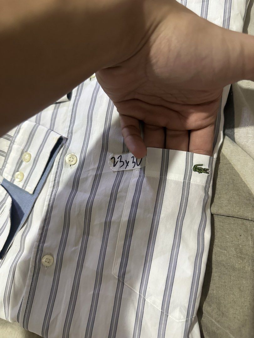 Lacoste Striped Button-Up Shirt Size 41 (Category: Tshirts & Polo Shirts ) located in Quezon City. Submitted by jeconiah.tayuman (Listing ID 1464549168, Image 2). Description: - Classic Lacoste button-up shirt - Color: White with thin blue stripes - Size: 41 (23x30) - Features a chest pocket - Ideal for smart casual outfits - Selling as it's no longer needed.