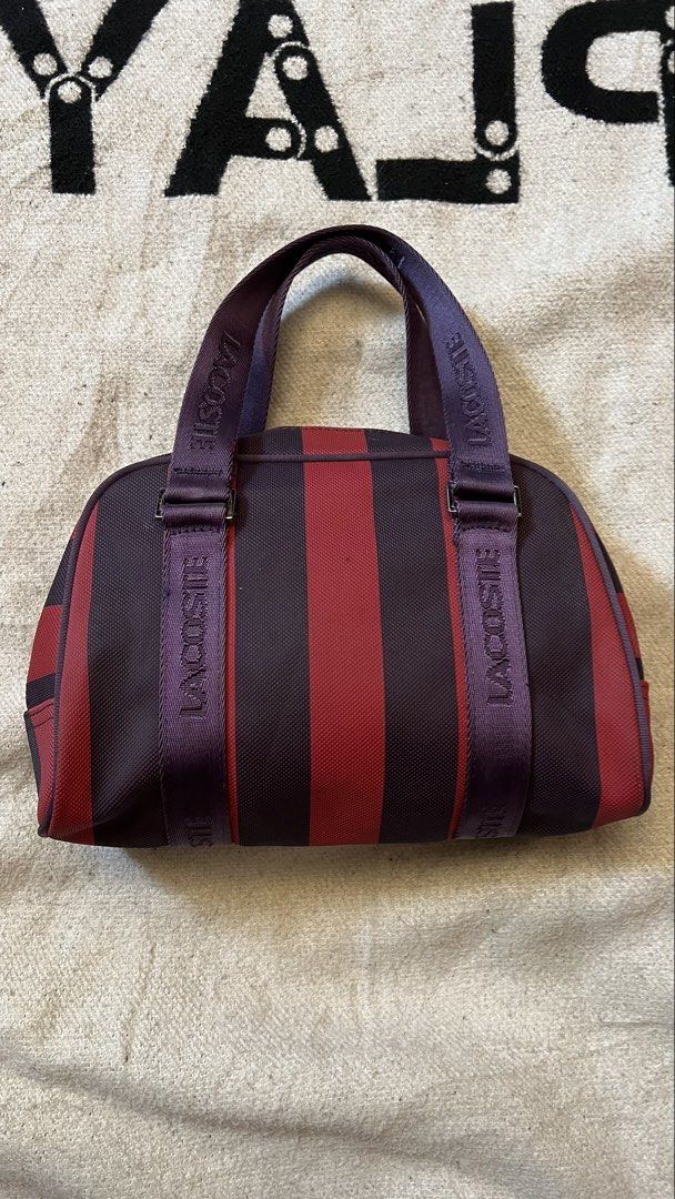 Lacoste Striped Duffle Bag (Category: Sling Bags) located in Cagayan de Oro. Submitted by nelsondel21723 (Listing ID 1464390550, Image 2). Description: - Stylish Lacoste duffle bag - Eye-catching red and purple stripe design - 'LACOSTE' branded straps - Secure zipper closure with branded pulls - Interior clip for keys or small pouch - Ideal for gym sessions or short trips.
