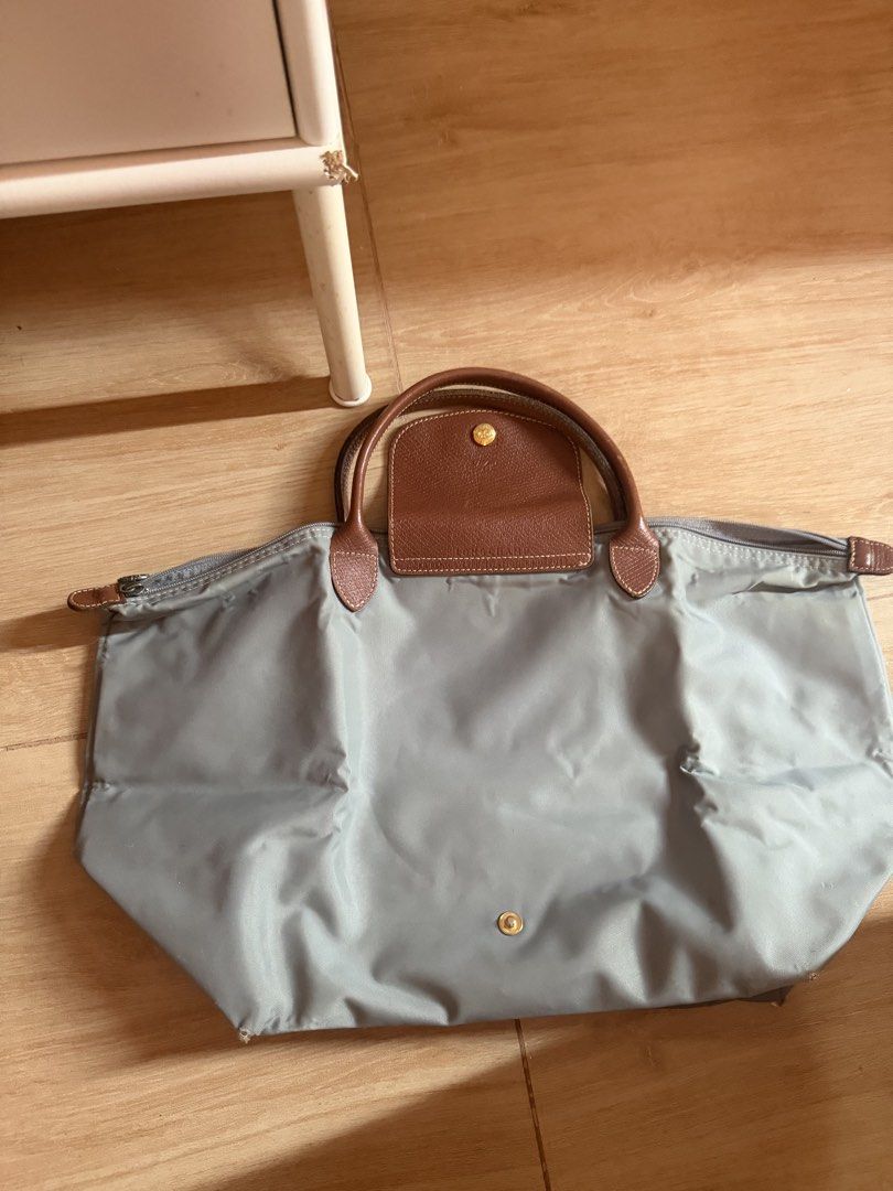 Longchamp Le Pliage Tote Bag Grey (Category: Luxury Bags & Wallets) located in Santa Rosa. Submitted by decluttering_. (Listing ID 1464363104, Image 2). Description: - Classic Longchamp tote bag - Grey nylon with brown leather handles and trim - Zips closed for security - Spacious interior for essentials - Ideal for work or travel - Note: Some marks and wear on the interior lining.