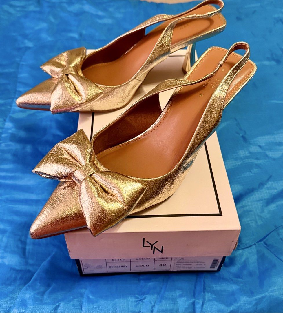 LYN Bowberry Gold Slingback Heels Size 40 (Category: Heels) located in Quezon City. Submitted by letsforsale (Listing ID 1464361918, Image 1). Description: - Brand: LYN - Color: Gold - Style: Slingback Heels - Size: 40 - Features: Cute bow detail, pointed toe, block heel - Condition: Comes with original box.