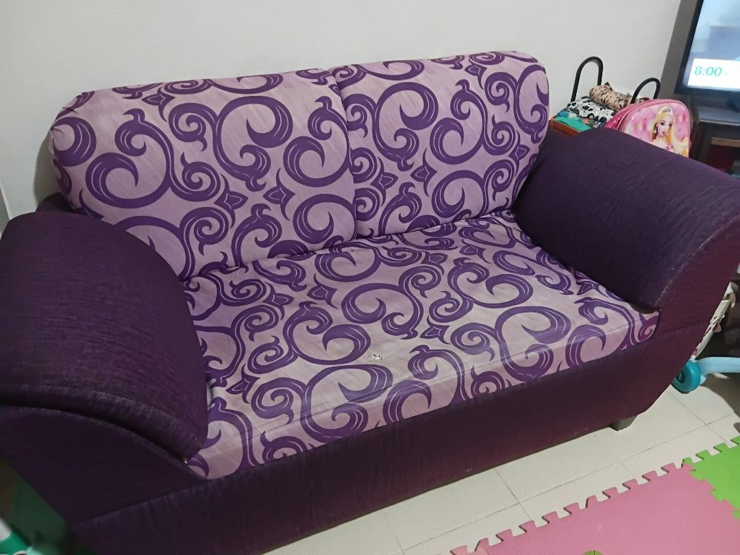 Mandaue Foam Sofa (Category: Sofas) located in San Jose del Monte. Submitted by lenlawliet (Listing ID 1464378479, Image 1). Description: - 60 in length x 31 in width x 15-32 in height - Two-seater sofa with a distinctive purple swirl pattern. - Seat cushion has a minor tear with some exposed foam and metal wires that can still be fixed. - Features a darker purple fabric base. - Ideal for compact living rooms or as additional seating. -Regularly 