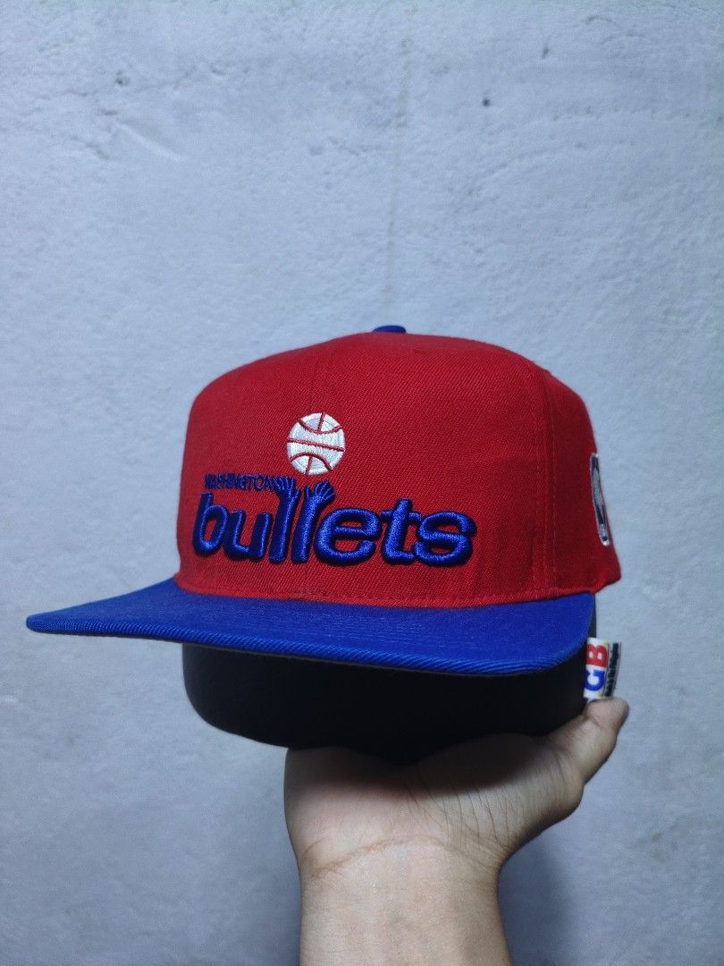 Mitchell & Ness Washington Bullets Snapback Cap (Category: Caps & Hats) located in Malilipot. Submitted by aronbigorn96320 (Listing ID 1464470329, Image 1). Description: - Mitchell & Ness Washington Bullets snapback cap - Classic red and blue colorway - Features embroidered 'Bullets' logo on front - 'Mitchell & Ness' embroidered on the back - NBA logo detail on the side - Adjustable snapback closure for a custom fit - Ideal for any Washington Bul